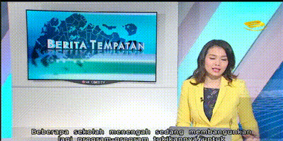 A female news anchor in a yellow blazer presents in front of a screen showing "Berita Tempatan" with Malay subtitles below.